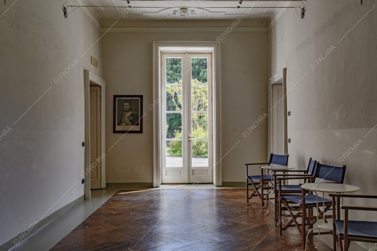 Stanza con boiserie sul soffitto bianco, porta-finestra e pavimento in parquet a spina di pesce