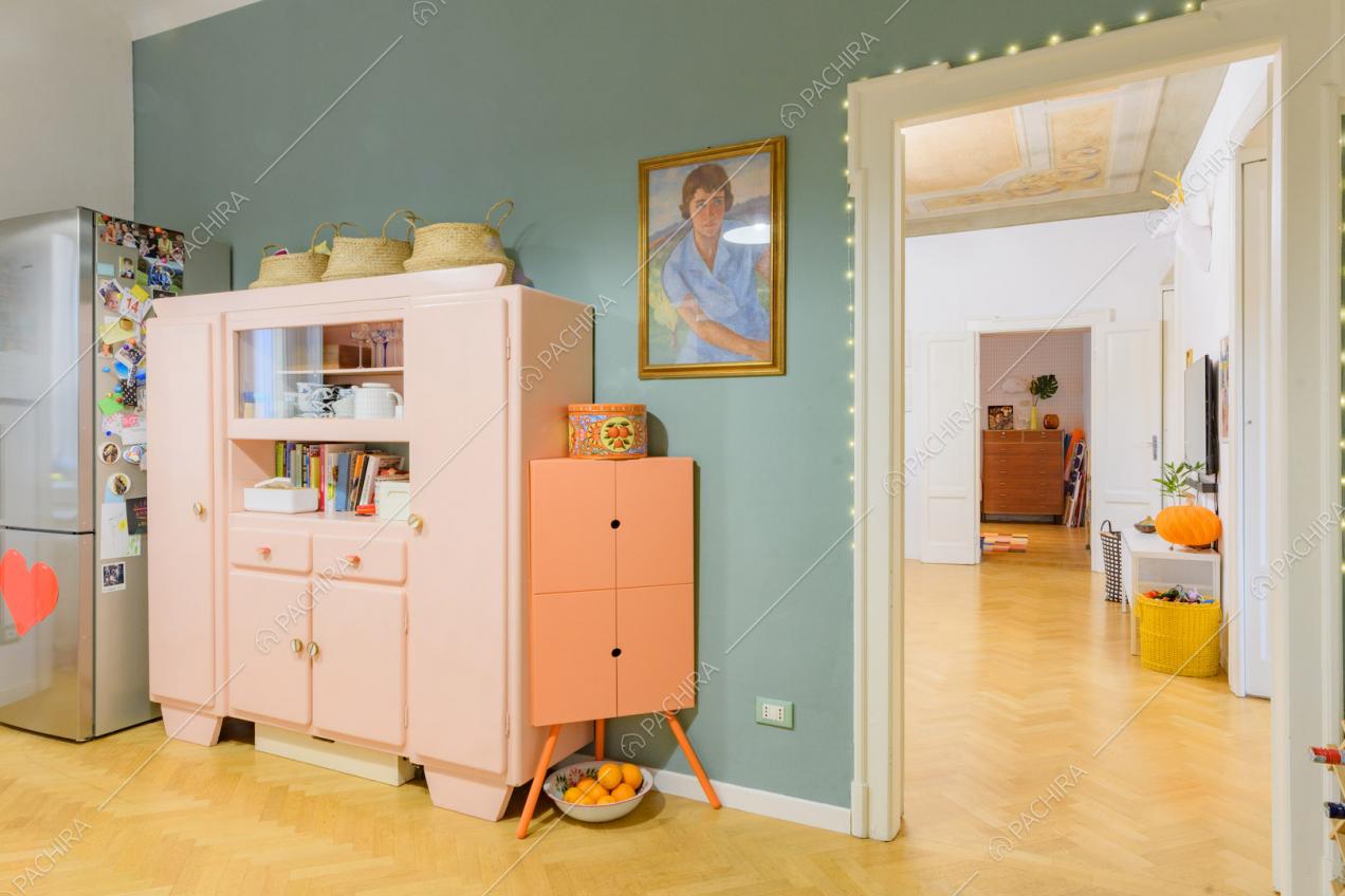 Credenza rosa nella cucina con parete azzurra e pavimento in parquet a spina di pesce