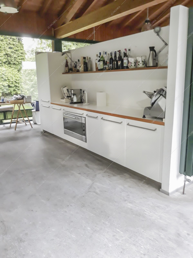 Cucina bianca a muro nello chalet con soffitto in travi in legno a vista