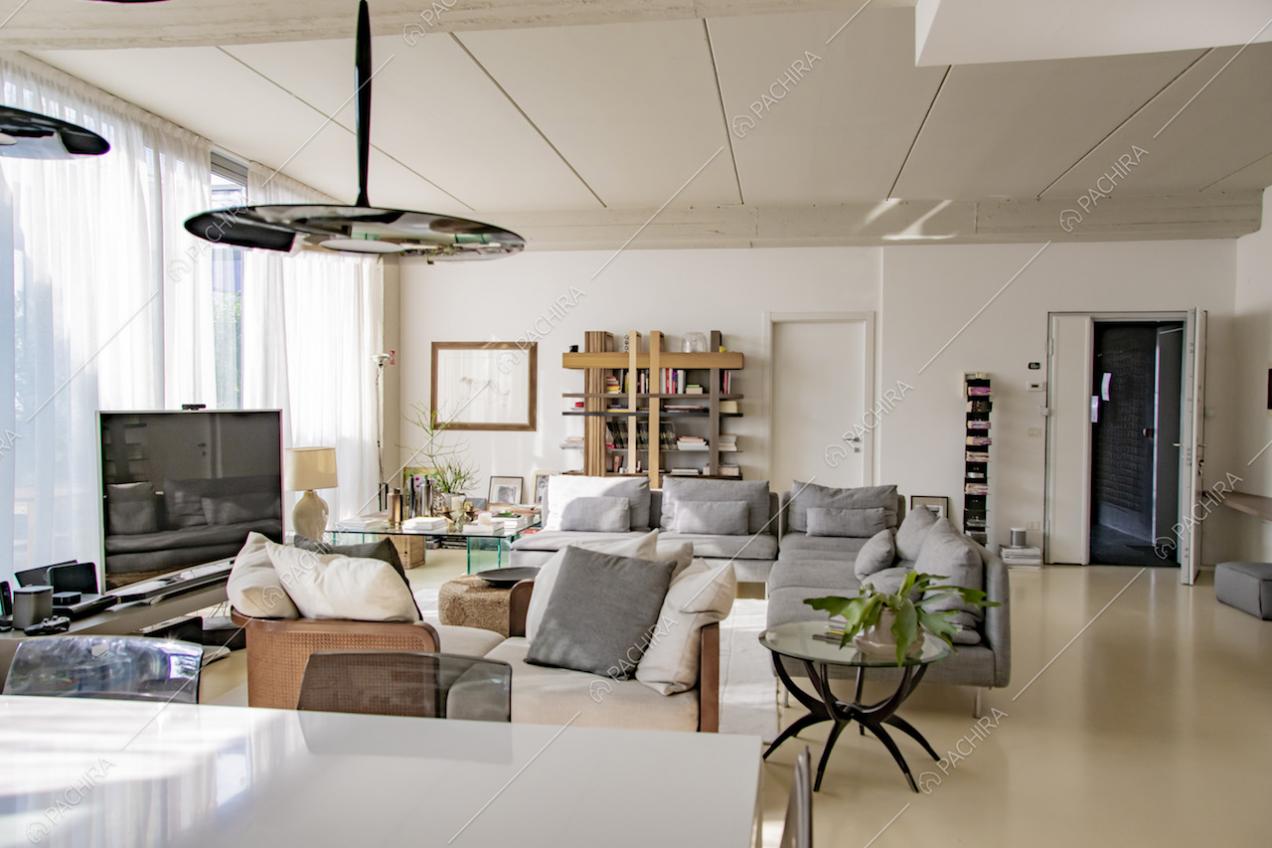 Zona living con divani, libreria e porta d'ingresso