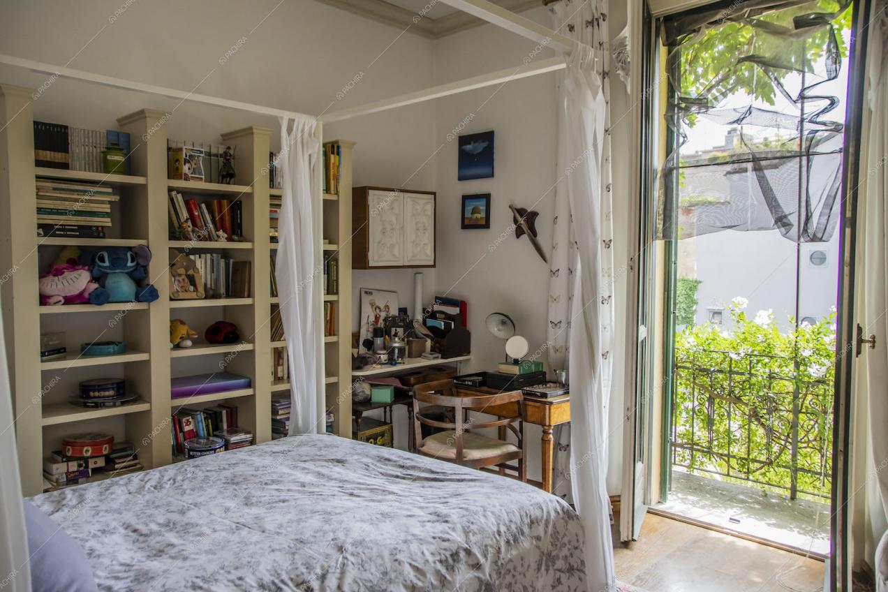 Luminosa camera da letto con struttura a baldacchino, pavimento in parquet e porta-finestra
