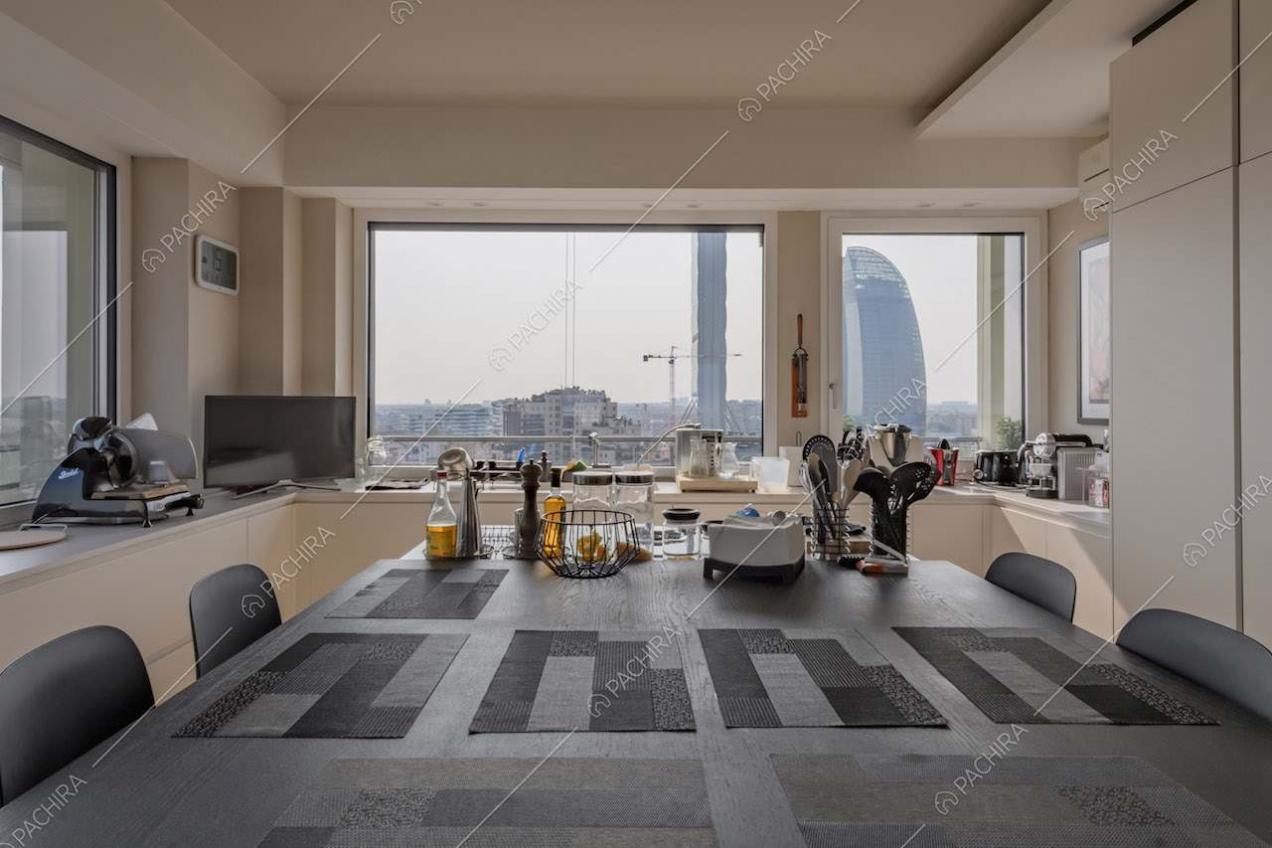 Cucina con isola e tavolo accostato e vetrate con vista sullo skyline