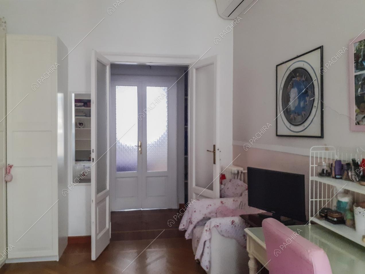 Parete bianca e rosa, armadio bianco, poltrona e televisione nella cameretta