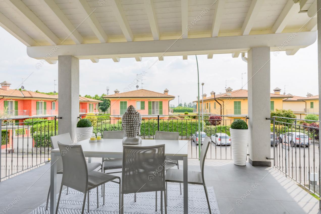 Tavolo da pranzo sulla terrazza coperta da un soffitto in travi bianche a vista