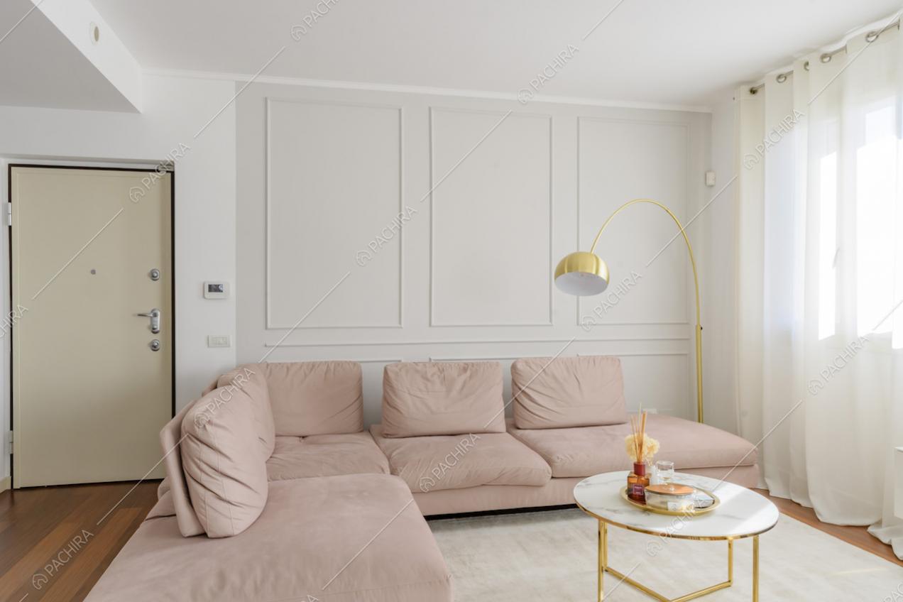 Divano rosa angolare con pavimento in parquet e boiserie alle pareti