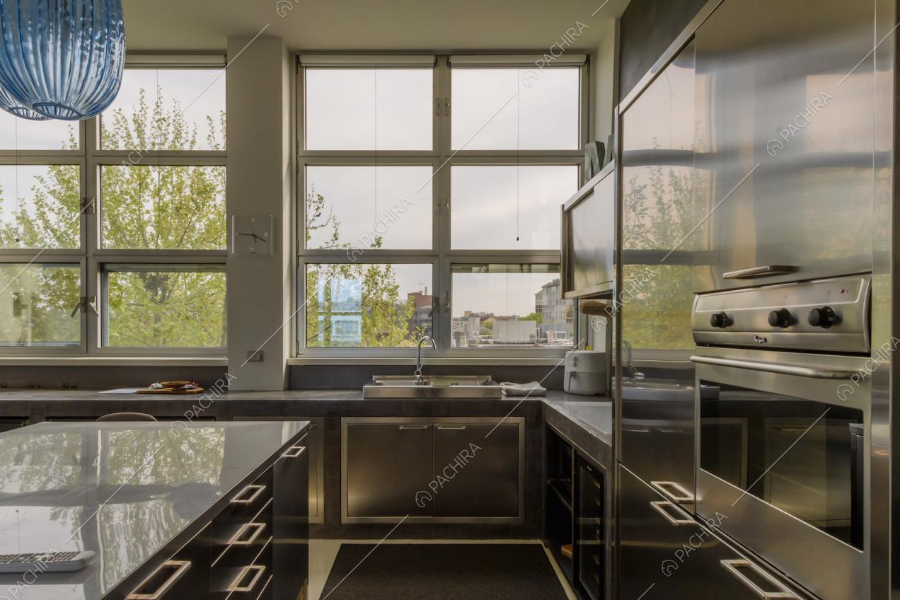 Cucina a isola con elemento in metallo e finestre in stile industriale