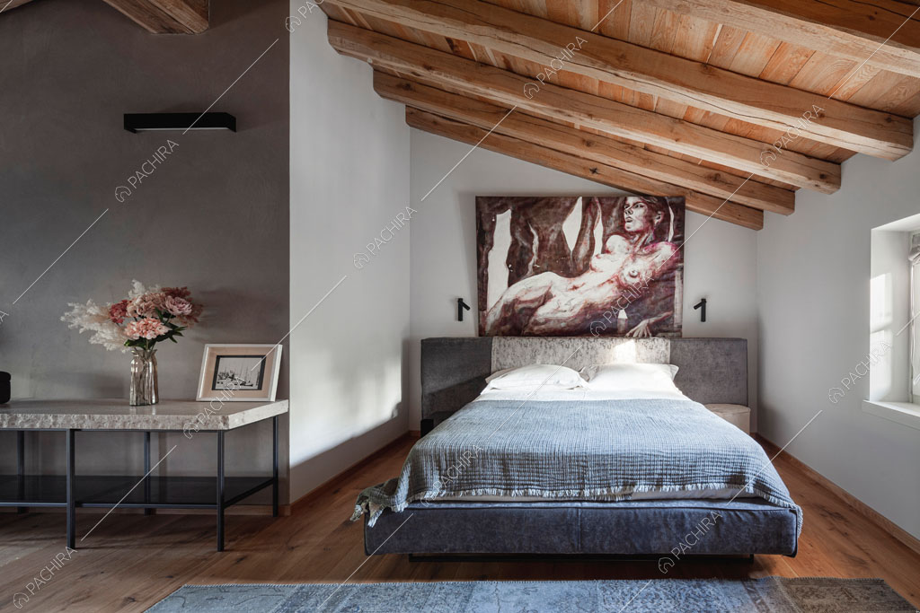 Camera da letto con travi a vista sul soffitto nella villa Ghibli, location in stile contemporaneo a Verona