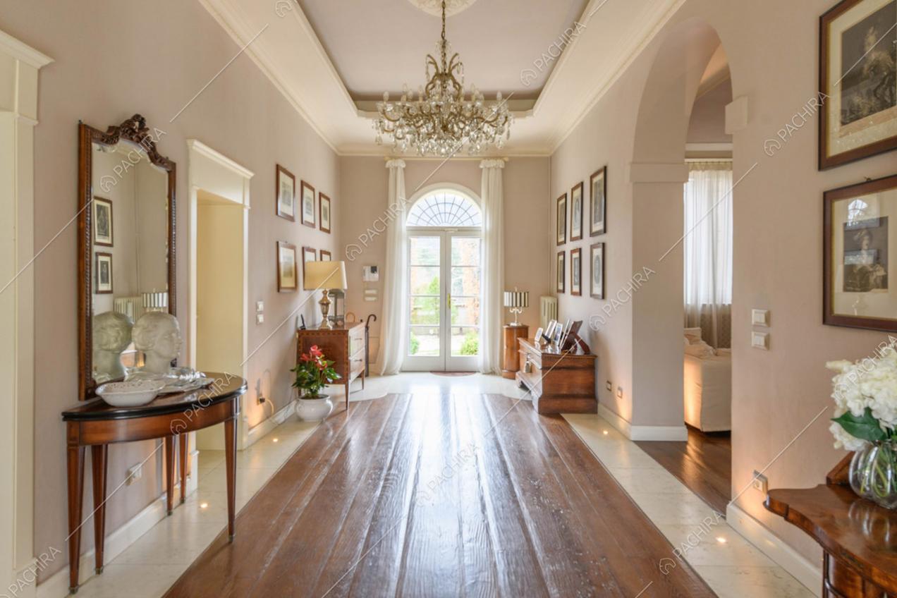 Grande corridoio con pavimento in parquet, lampadario antico e porta-finestra