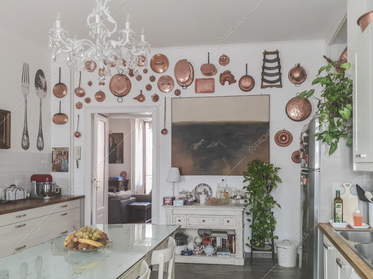 Pentole in rame di varie dimensioni appese alla parete in cucina