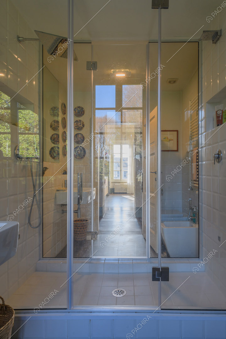 Luminoso bagno con box doccia dal pavimento in piastrelle bianche