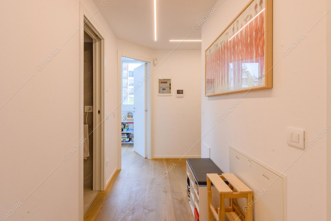 Luminoso corridoio con pavimento in parquet e vista su bagno e camera dei bambini