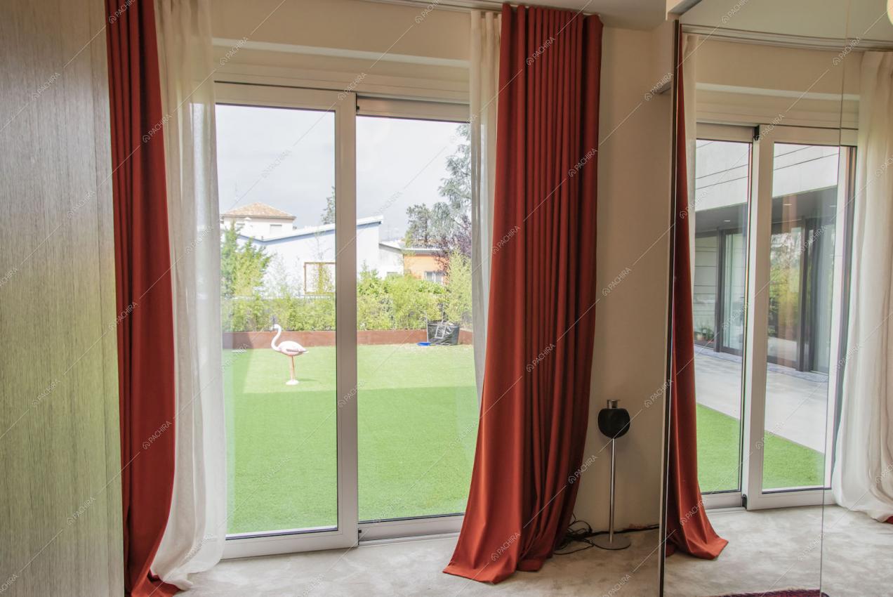 Porte-finestre scorrevoli con tende rosse e vista sul giardino