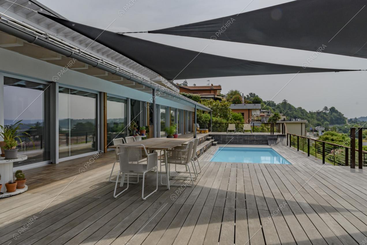 Terrazza con pavimento in parquet da esterni, tavolo da pranzo, vetrate e piscina con vista sul lago