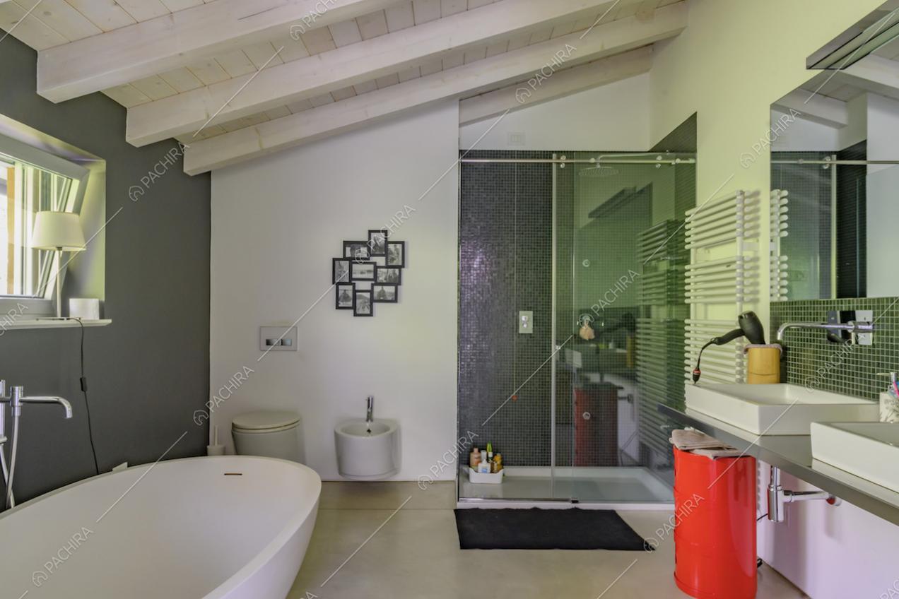 Ampio bagno dalle pareti bianche e grigie con vasca, doccia e doppio lavandino
