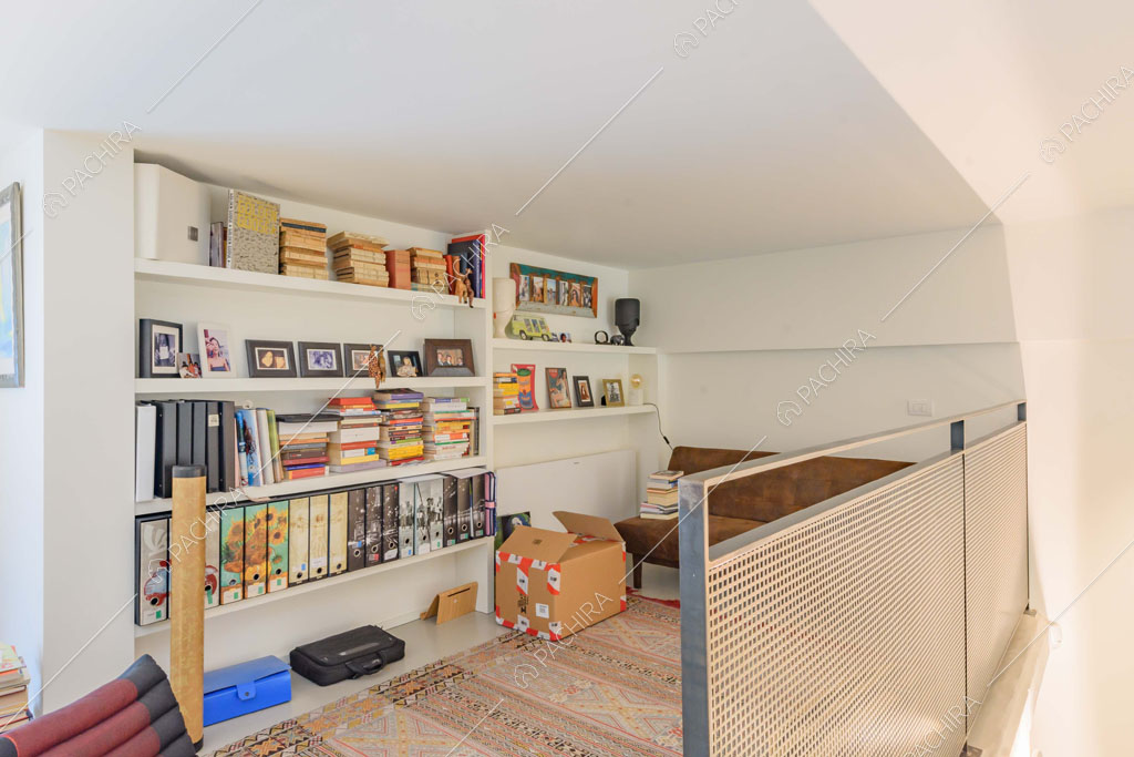 Soppalco con libreria, pareti bianche e balaustra in metallo