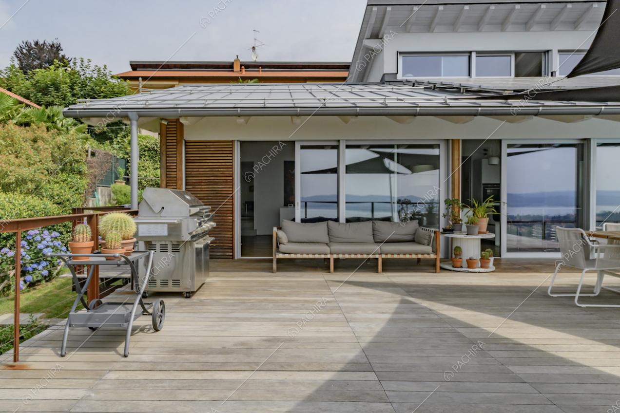 Terrazza con pavimento in parquet da esterni, barbecue, veranda con divano e porte-finestre scorrevoli