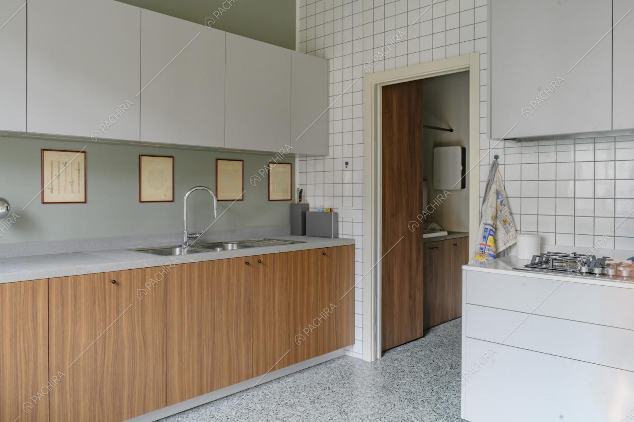 Cucina a muro con pareti verde e bianca a piastrelle, fornelli a gas e pavimento in marmo