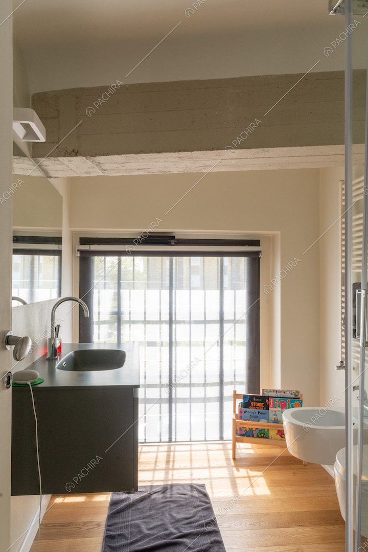 Bagno con mobile sospeso, pavimento in parquet e ampia finestra in stile industriale