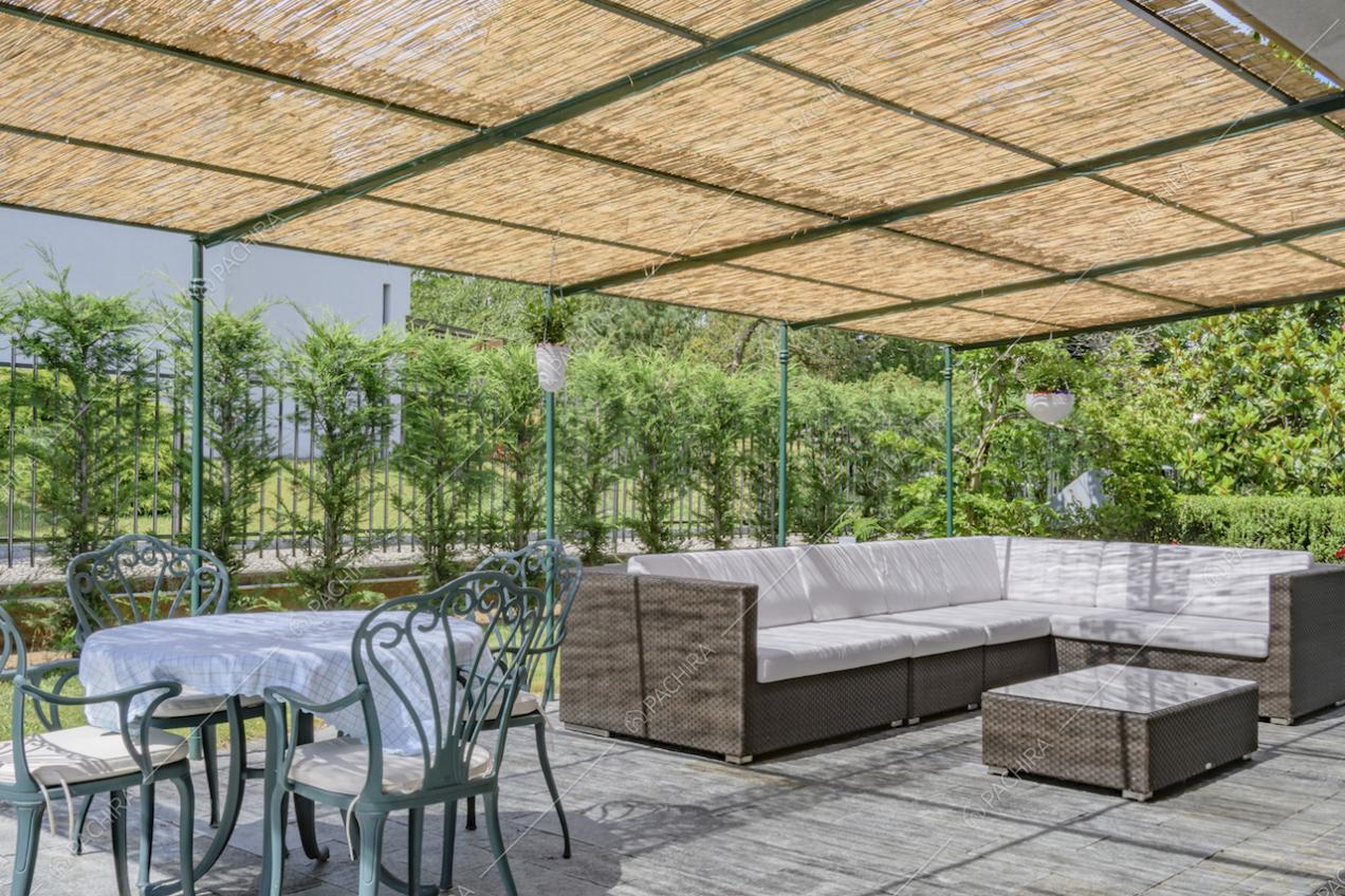 Veranda aperta con divano angolare in vimini e tavolo da esterni