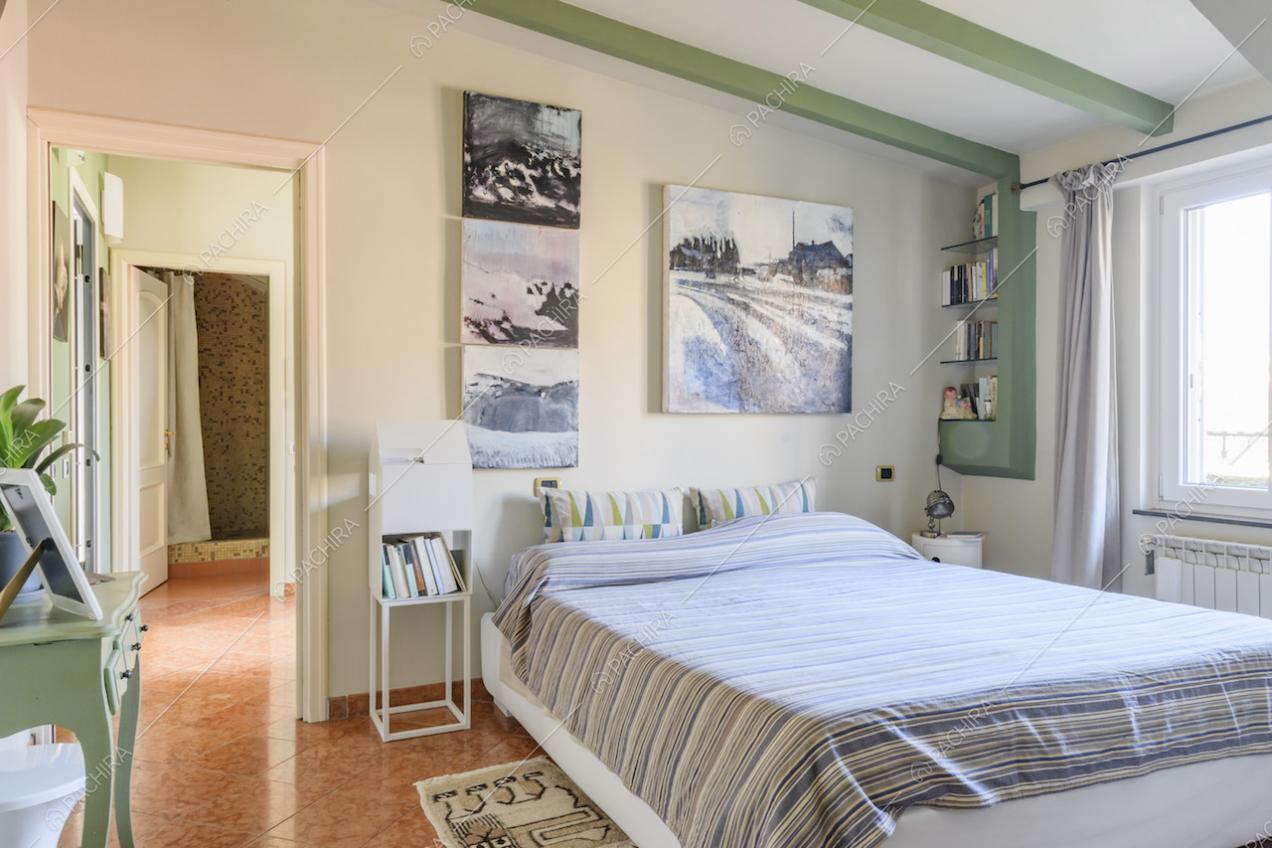 Letto, quadri appesi alla parete e finestra con tende bianche