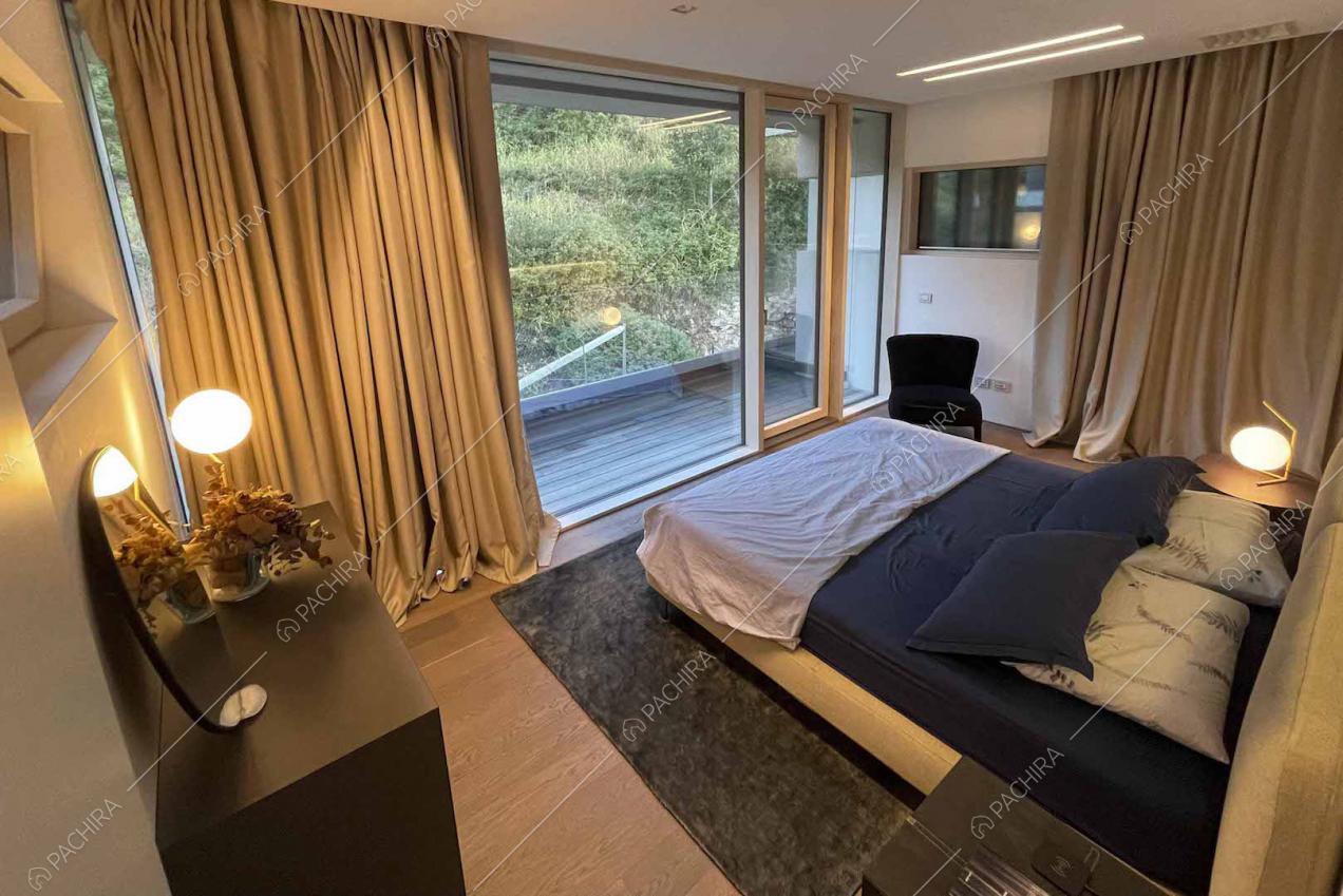 Camera da letto matrimoniale con ampie vetrate e accesso al balcone tramite porta-finestra scorrevole