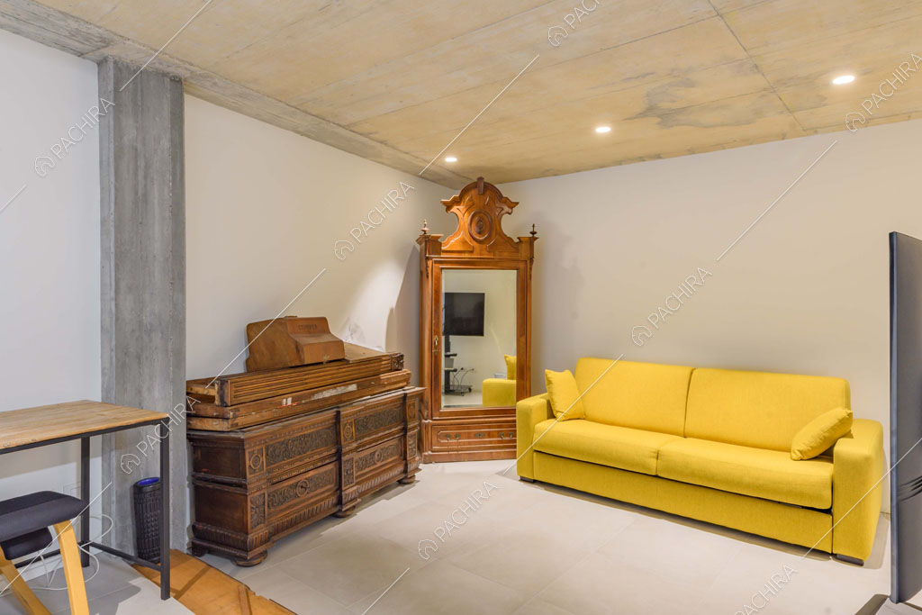 Divano giallo e soffitto in cemento nella luminosa stanza