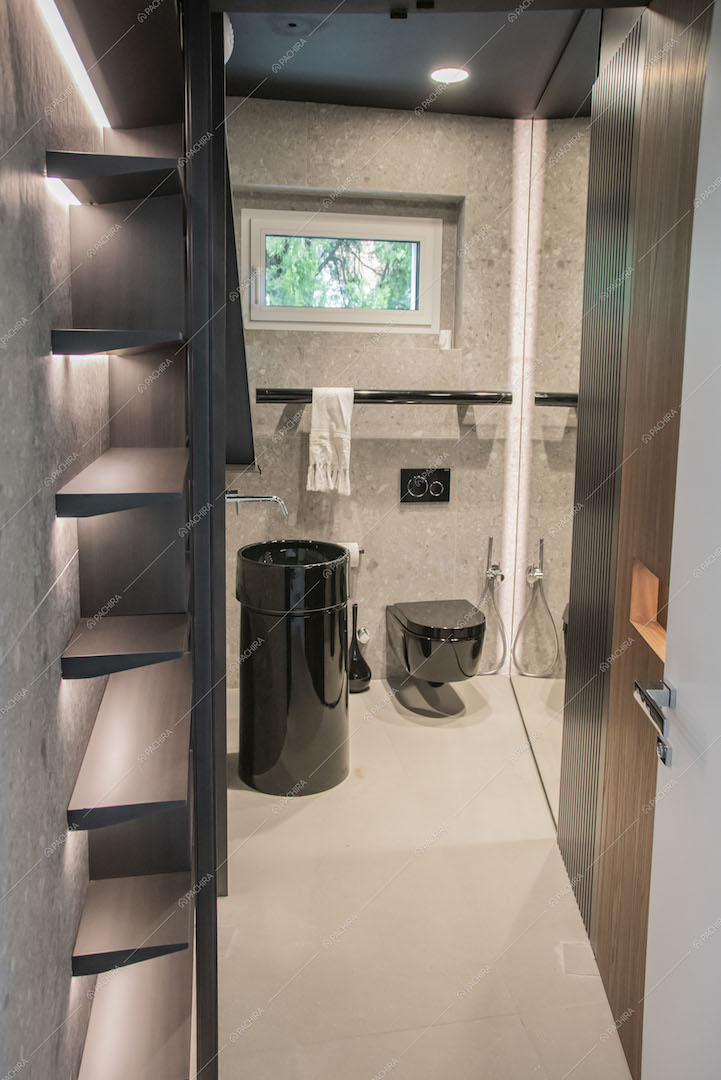 Parete in pietra nel bagno con sanitari neri e lavandino di design