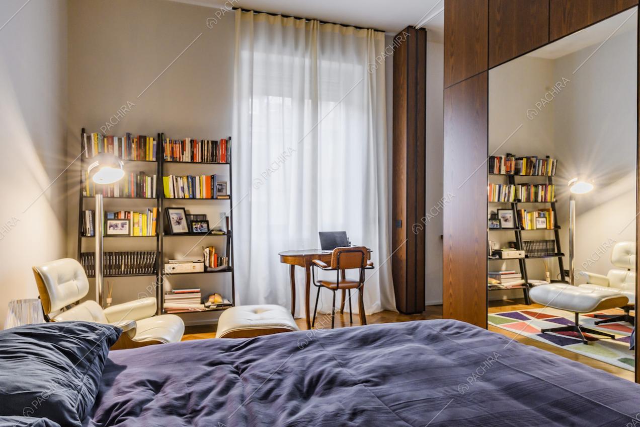 Camera da letto matrimoniale con specchio e poltrona bianca di design