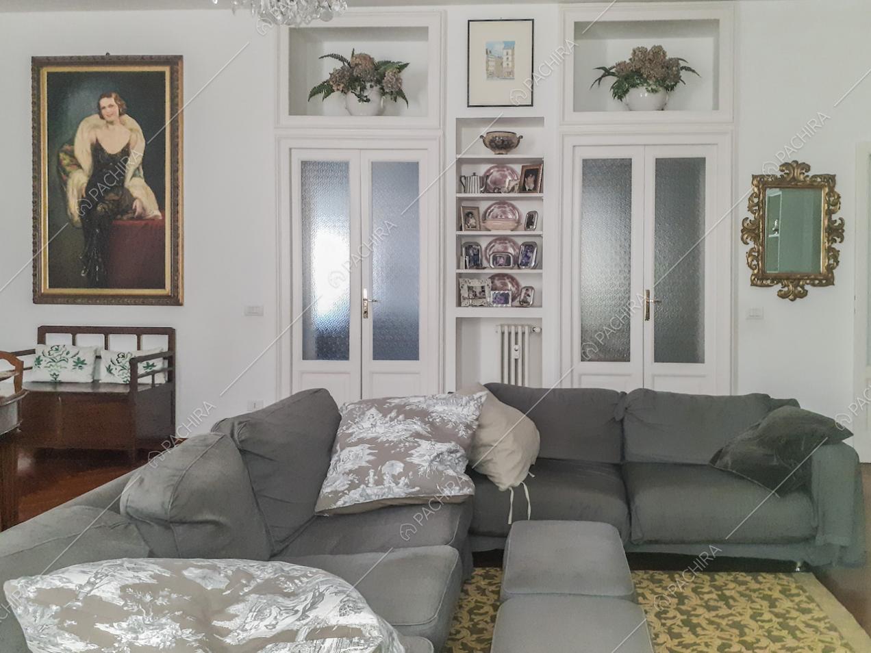 Portafoto e soprammobili sulle mensole nella parete bianca del salotto e divani grigi