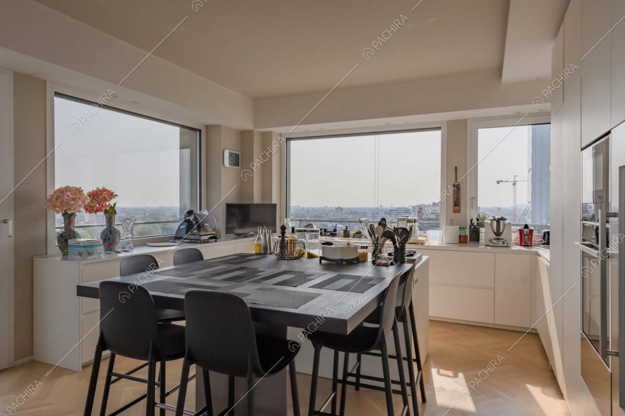 Vetrate con vista sullo skyline nella cucina a isola con tavolo accostato