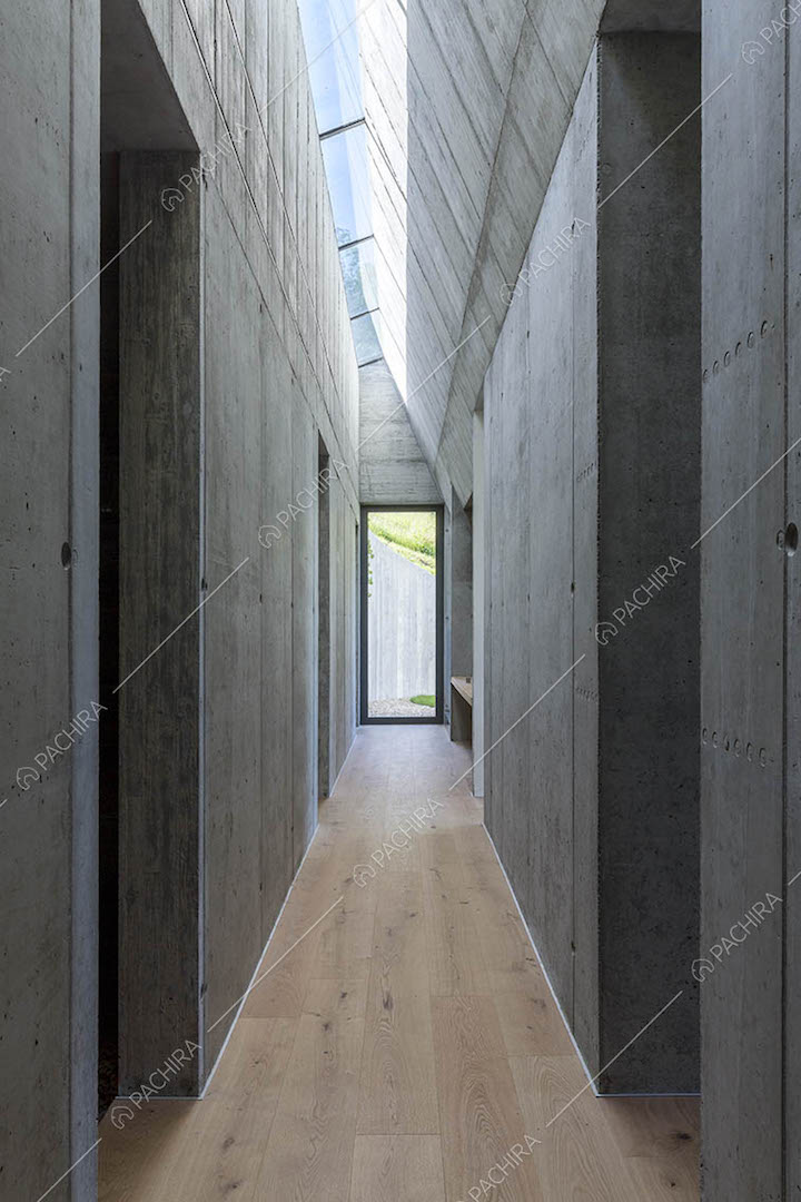 Corridoio con pavimento in parquet, pareti in cemento e lucernari