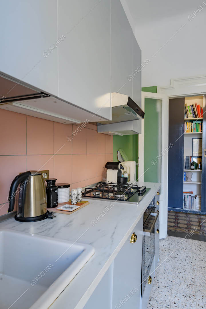 Piano da lavoro in marmo nella cucina a parete con fornelli a gas e paraschizzi rosa