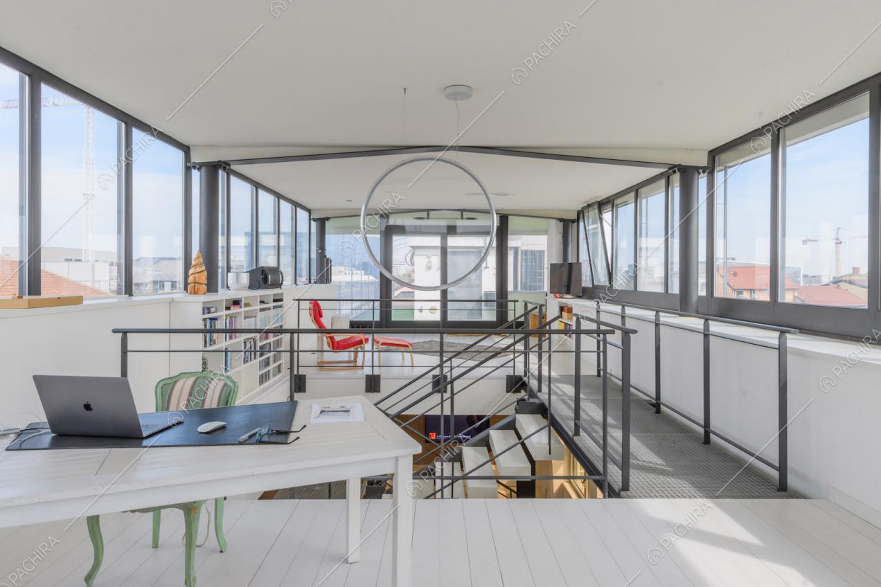 Studio al piano superiore della location con vetrate su ogni parete e pavimento bianco