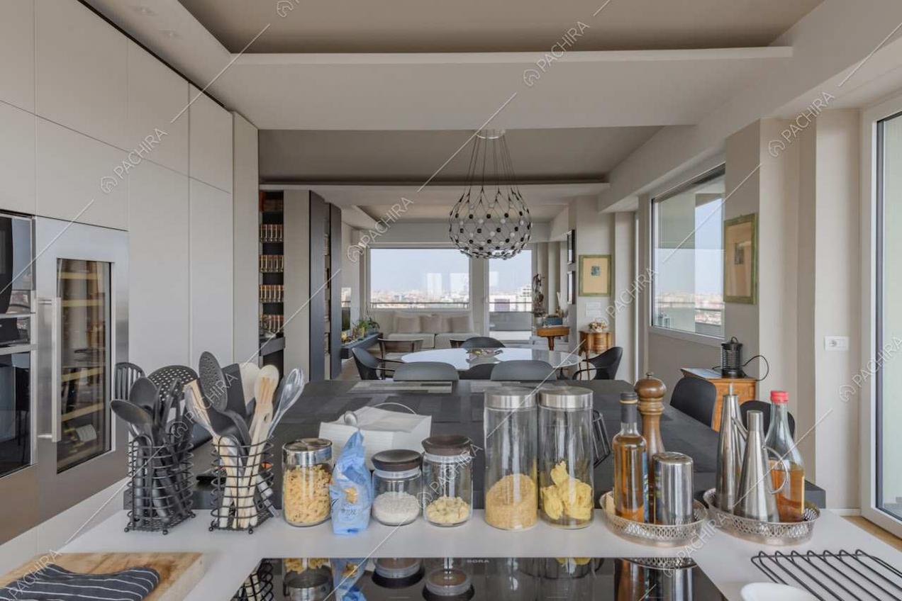 Fornelli a induzione sull'isola della cucina con tavolo accostato e vista sulla sala