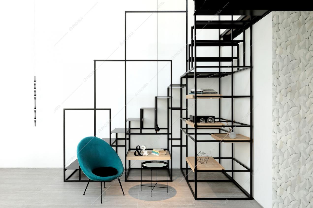 Particolari scale nere in metallo che poggiano su una libreria e poltrona di design
