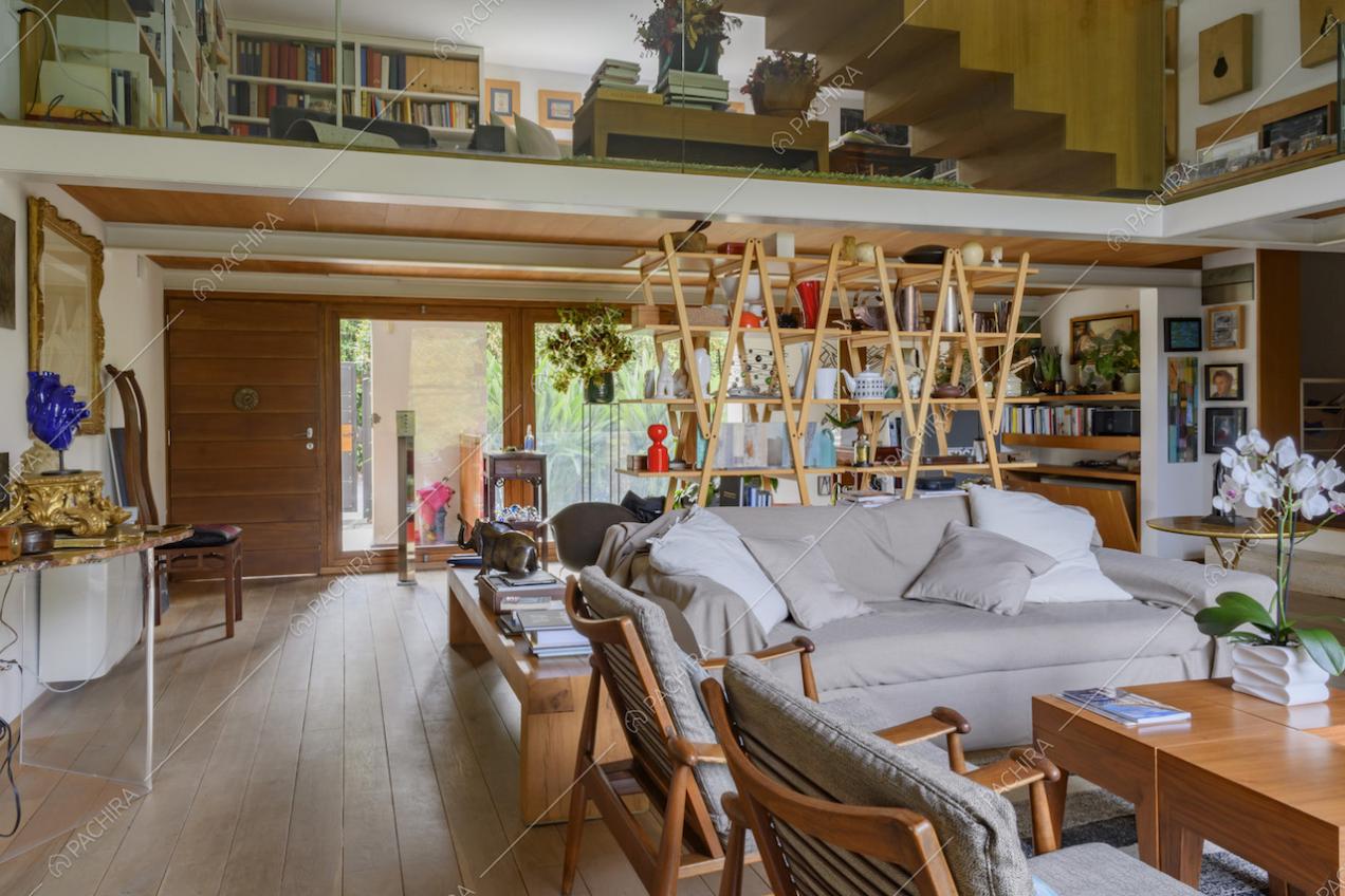 Soggiorno con poltroncine in legno, divano e libreria in legno