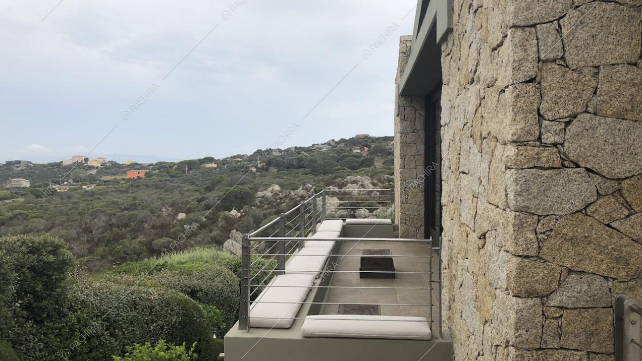 Cuscini bianchi sulla terrazza con ringhiera in ferro e pareti in pietra