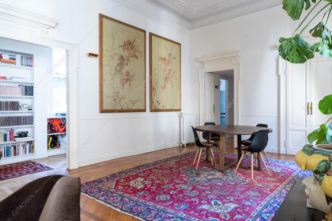 Dal salotto con boiserie sul soffitto vista sul tavolo da pranzo in legno e sulla camera da letto