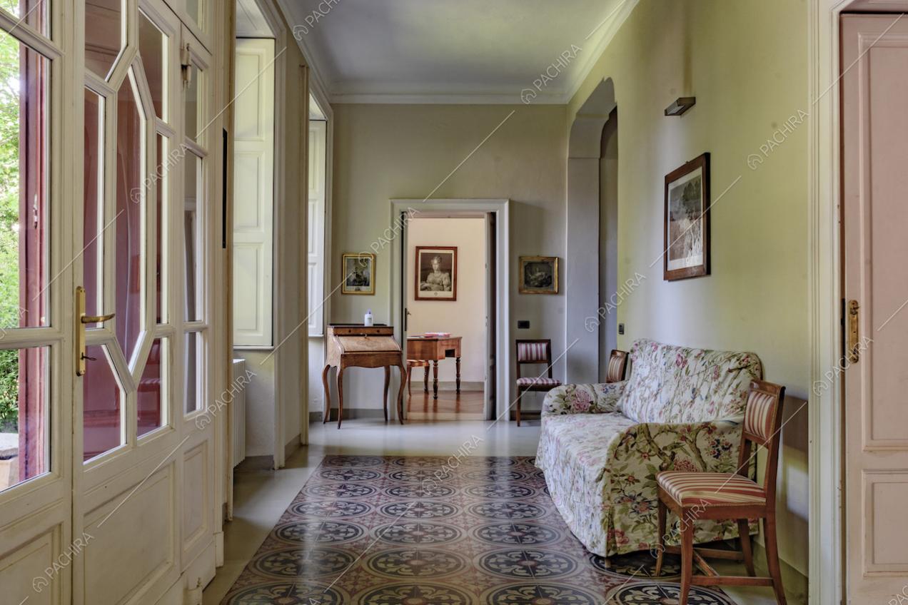 Ingresso della location, tramite porta a vetri bianca, nell'ampio corridoio dalle pareti verdi e con boiserie sul soffitto
