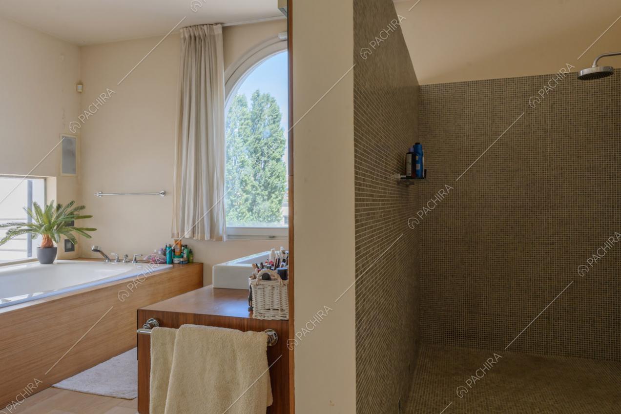 Grande box doccia e vasca nel luminoso bagno con pavimento in parquet