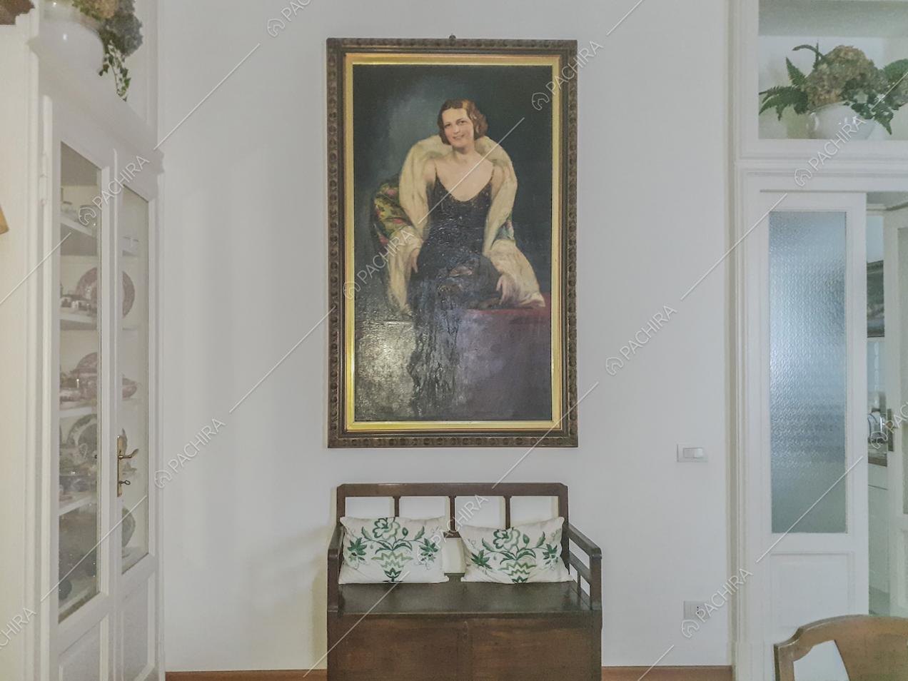 Dipinto con ritratto d'epoca appeso alla parete e panca d'antiquariato