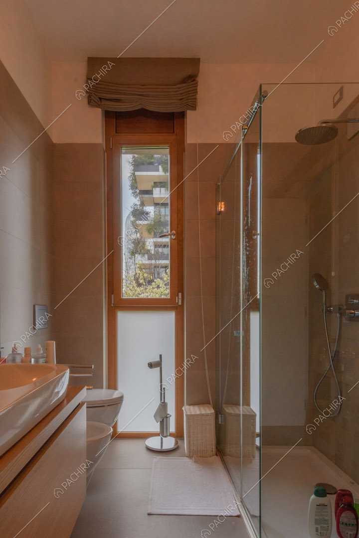 Bagno con box doccia e piastrelle grigie su pavimento e pareti