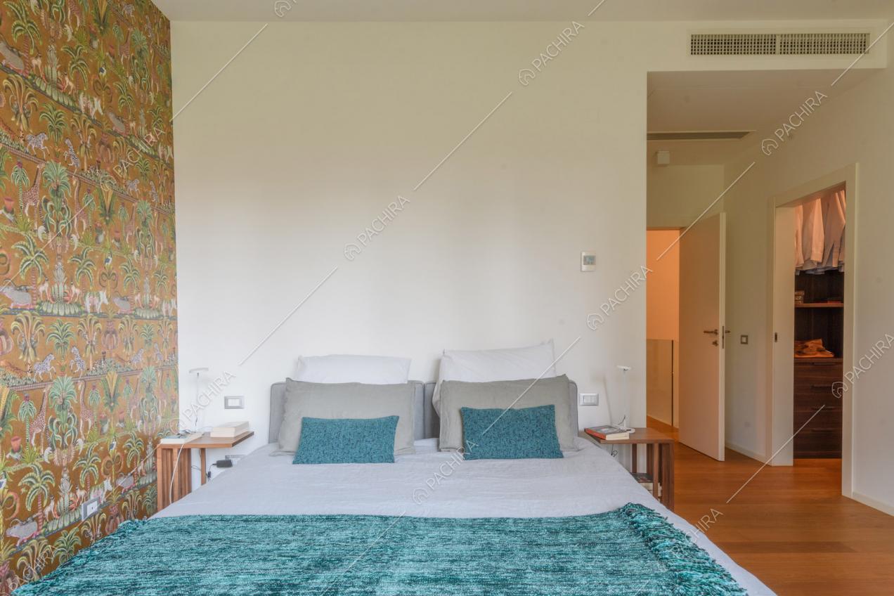 Luminosa camera da letto matrimoniale con carta da parati e cabina armadio