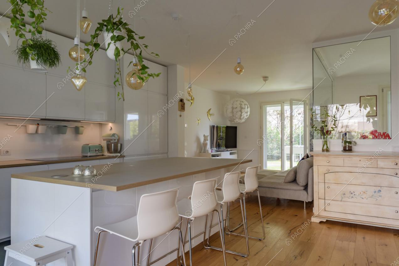 Dalla cucina con isola vista sul salotto e sulla vetrata che separa lo studio dall'open space