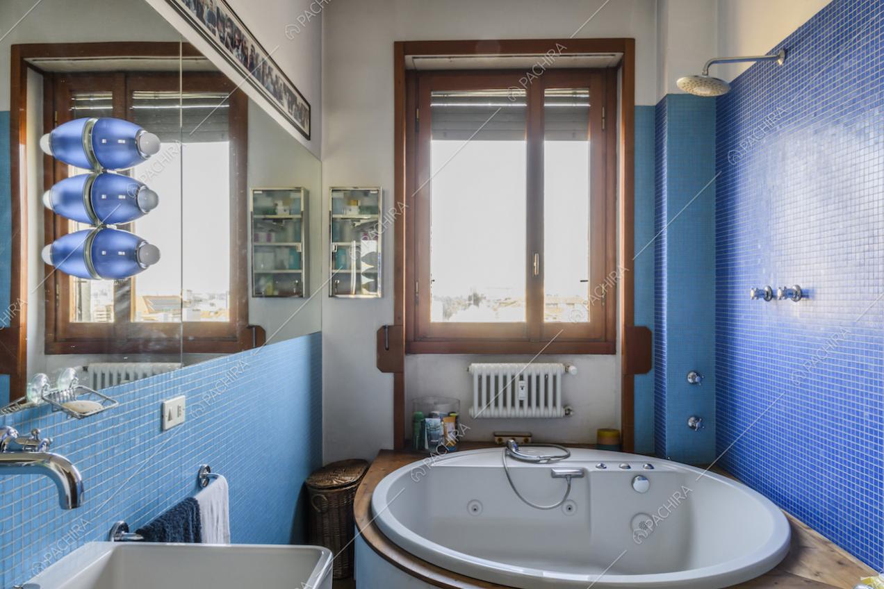 Vasca idromassaggio e pareti rivestite con piastrelline a mosaico blu