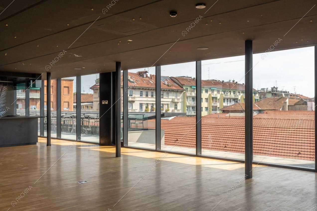 Salone con vista sullo skyline di Milano attraverso le grandi vetrate e pavimento in parquet