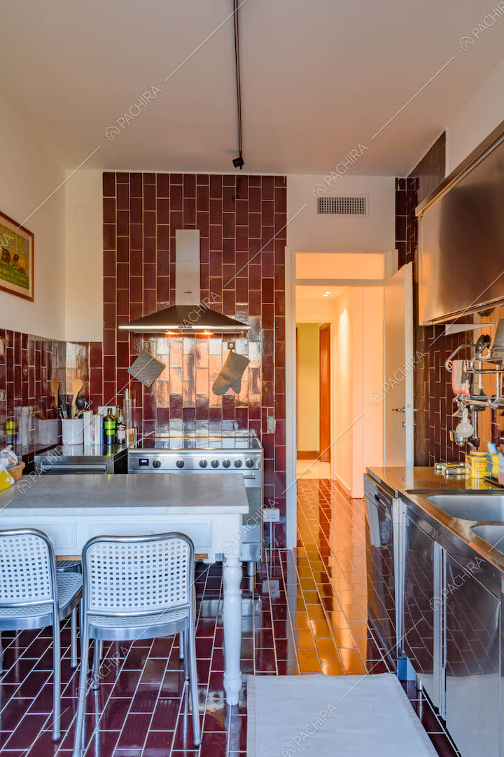 Cucina a parete con pavimento e pareti in piastrelle rosse, fornelli a induzione e tavolo da pranzo