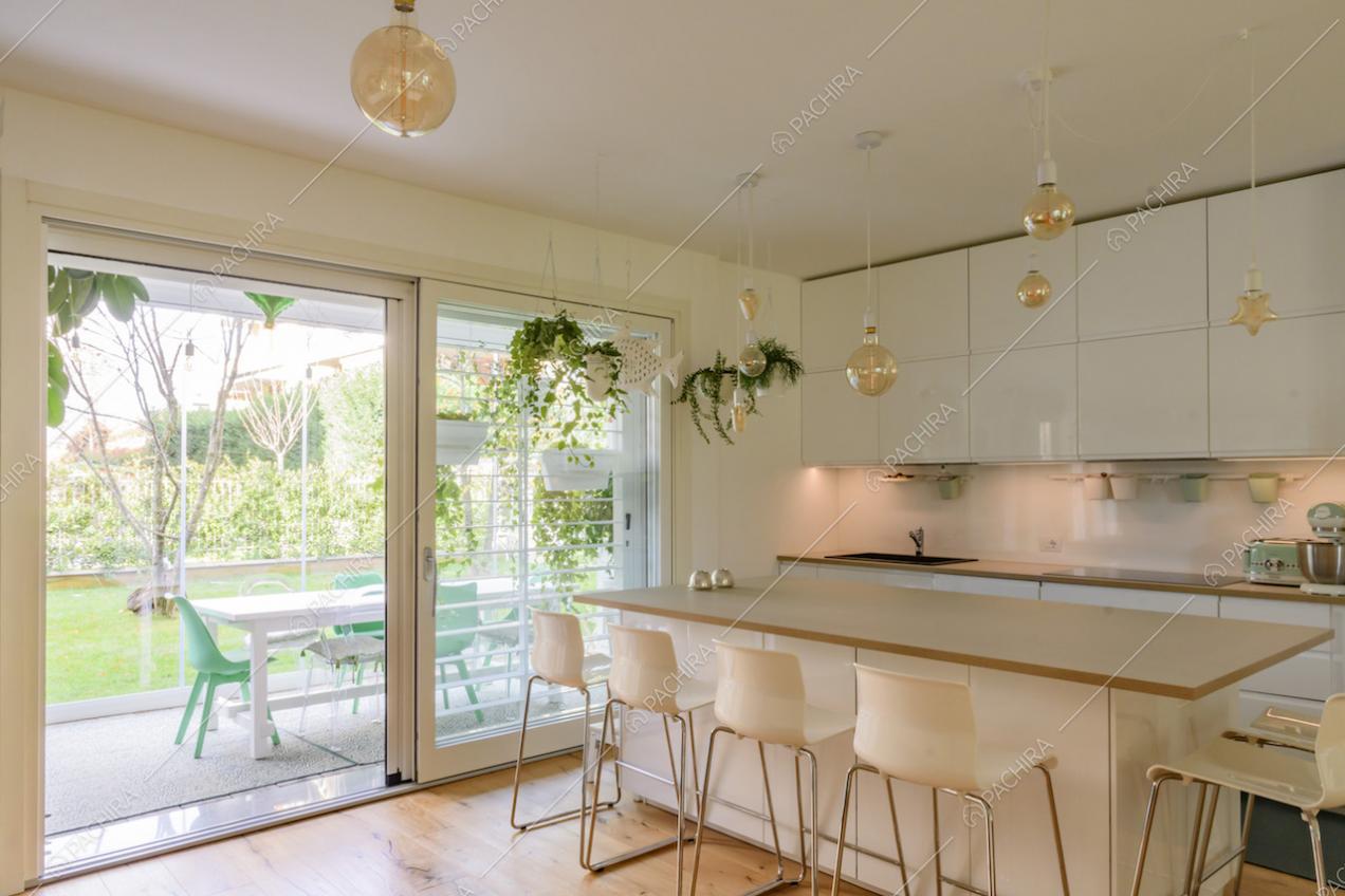 Cucina con isola e accesso alla veranda con tavolo da pranzo tramite porta-finestra scorrevole