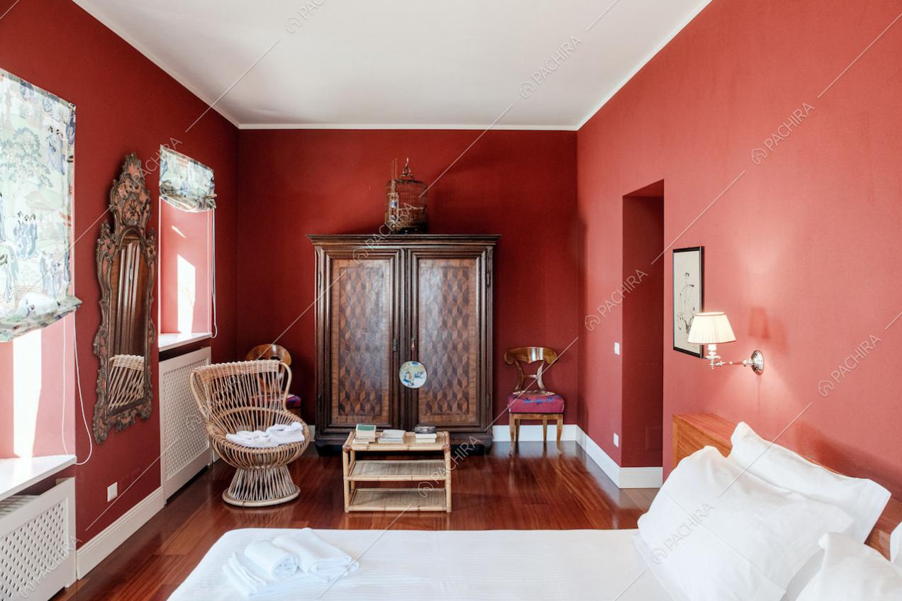 Camera da letto con pareti rosse e pavimento in parquet