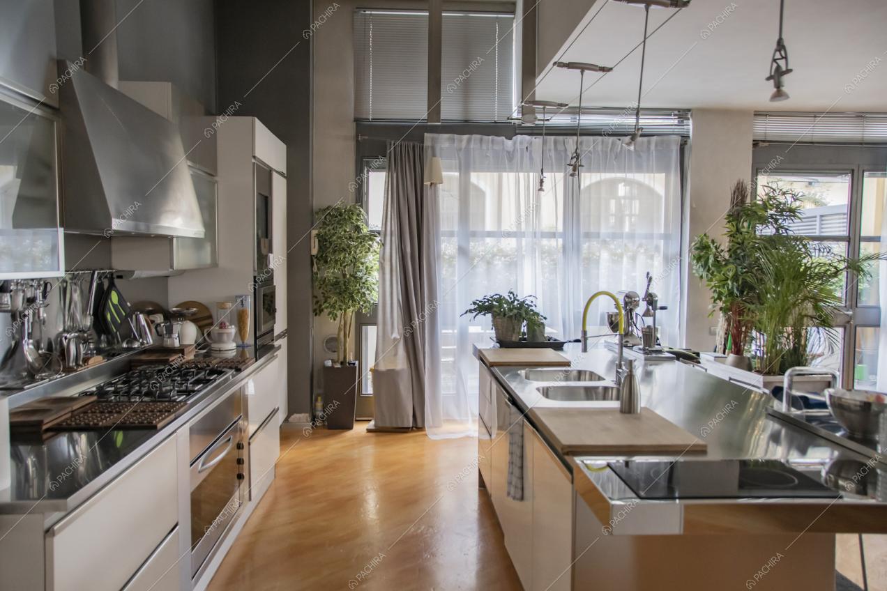 Luminosa cucina a isola con fornelli a induzione e a gas e pavimento in parquet